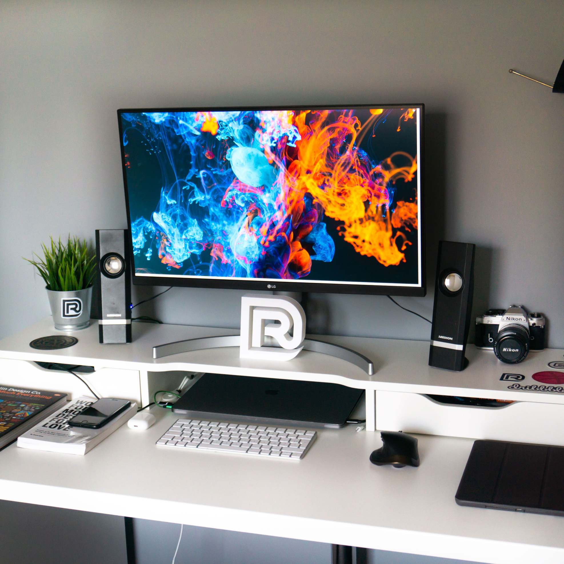Office desk with a widescreen monitor displaying colorful artwork
