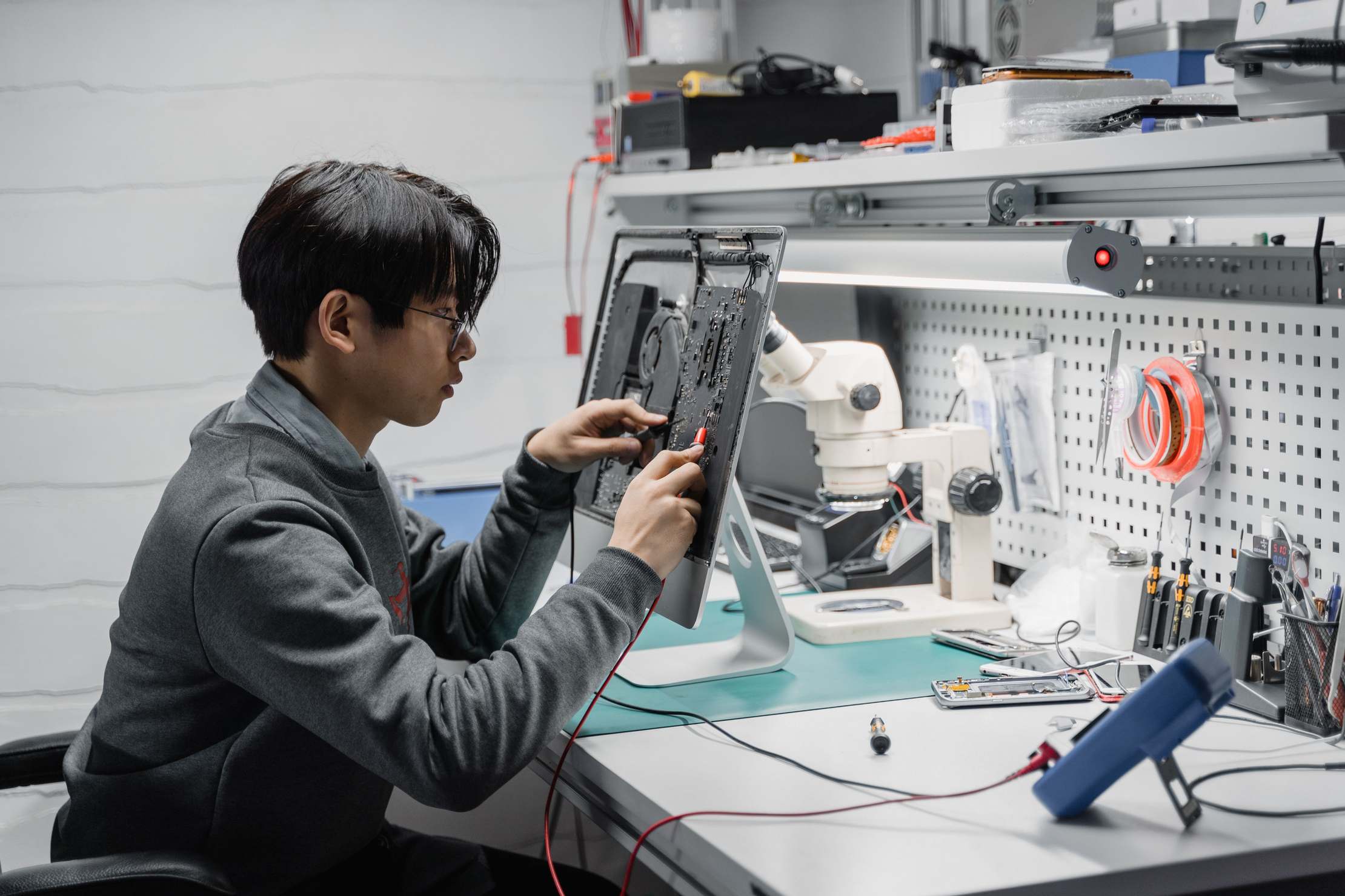 Technician working on electronic repairs at a tech lab workspace